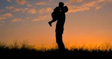 Loving father silhouette kissing his little child on the cheek