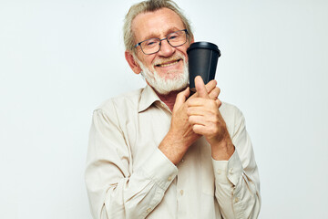 Naklejka premium Portrait of happy senior man with a gray beard in a shirt and glasses light background