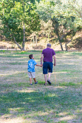 Obraz premium Little kid and elderly man walking in the field
