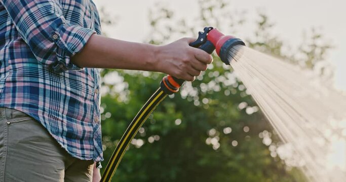 The gardener's hand pours a garden hose with a diffuser