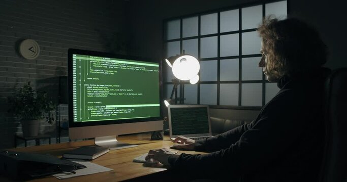 Programmer using computer in dark room