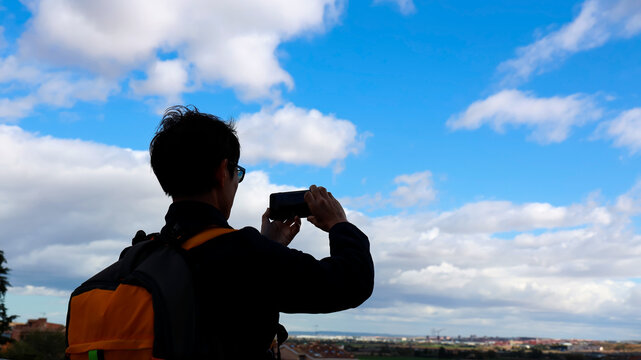 Back view of young tourist man hand which take a picture by Photo camera of a smartphone with blue sky scene in the city in Toledo spain.