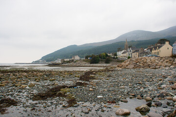 A view of the Mountains of Mourne  and Tollymore Forest Park from the stony breakwater on the beach at Newcastle County Down in Northern Ireland - obrazy, fototapety, plakaty
