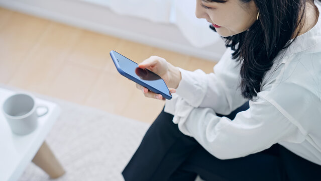 部屋でスマホを使う女性