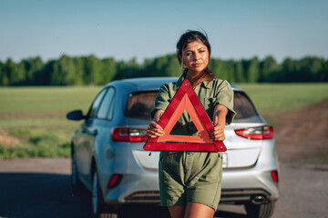 pretty brunette girl is holding an emergency triangular sign, blurred background