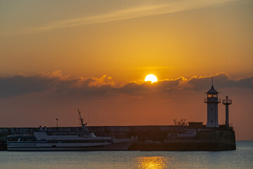 the sun rises from behind the Yalta lighthouse
