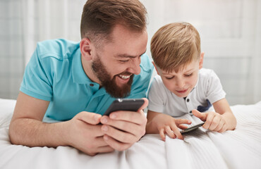 Fototapeta premium Father and son using smartphones together