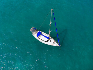 Fototapeta premium Aerial wonderful view of a enormous white and blue yacht sailing across the blue lagoona