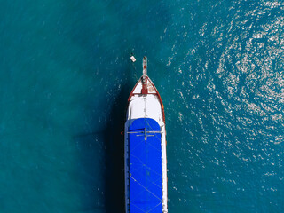 Top view of a huge white yacht with a blue roof is floating across the sea