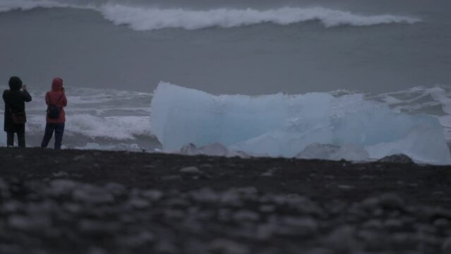 Spectacular waves breaking over huge icebergs on diamond beach