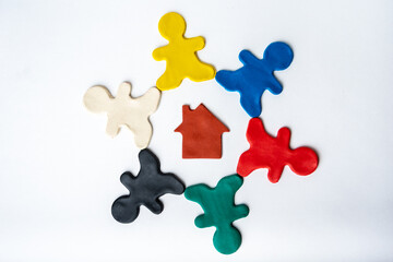 Brown plasticine house in the center of multi-colored bright plasticine men in a circle isolated on a white background