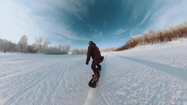 A male snowboarder rides a snowboard on a ski slope on a sunny day