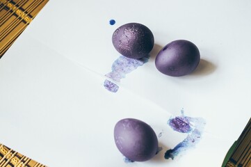 Dark purple colored Easter eggs on white paper, copy space
