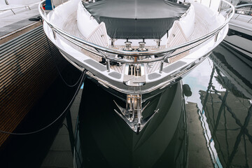 View on a bow of huge luxury white yacht standing on the black water on the parking lot, wide angle