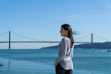 young girl with the 25 april bridge in the background, lisbon, portugal
