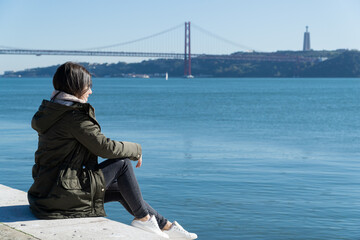young girl with the 25 april bridge in the background, lisbon, portugal