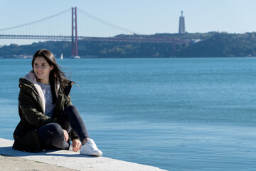 young woman with the 25 april bridge in the background, lisbon, portugal