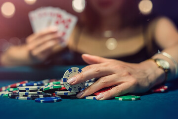 Fototapeta premium young attractive woman playing poker at table with stacks of chips and cards