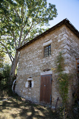 Fototapeta na wymiar vieille maison avec mur en pierre et un arbre