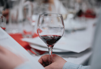 Glass of red wine in hand at a special event, a specific tasting of alcoholic beverages.