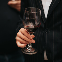 Glass of red wine in hand at a special event, a specific tasting of alcoholic beverages. - 482810507