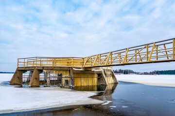 Yellow metallic bridge construction with viewing platform, concrete  spillway