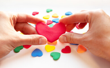 Hands holding red valentines on valentine's day. The girl's hands hold a lot of small hearts and fast-setting plasticine. The 14th of February. Holiday of love. The concept of giving love. give life