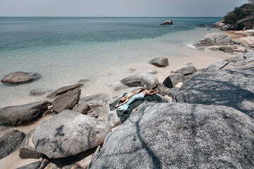 Fototapeta na wymiar two sexy fit mermaids are sunbathing on stones, on a fishnet