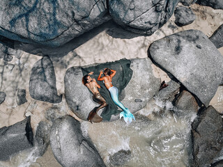 two beautiful mermaids are lying on the fishnet, on the stones, top view