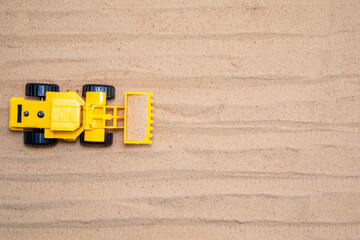 Toy tractors work in the sand Wooden toy car in cartoon style on yellow background. Colorful and...