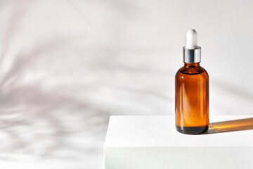 Fototapeta premium Essential oil on a gray background with shadows. Cosmetic medical beauty product in brown glass bottle with a pipette for aromatherapy, alternative medicine.