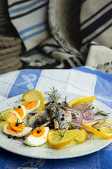 Herring fish fillets with eggs, herbs, onion and lemon on a white plate