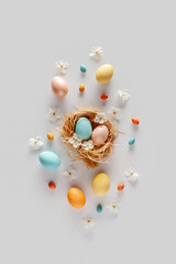 Easter composition in pastel colors. Eggs, candies and flowers on a white background. Flat lay. 