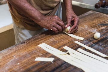 Man's hands cutting cheese on a wooden table
