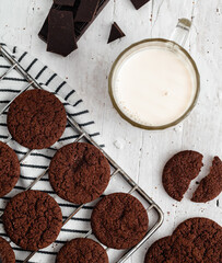 Fresh chocolate cokies and glass of milk on a white wooden background. Top view.