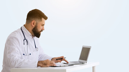 Healthcare, medicine concept: Doctor is working with documents and laptop in his medical office isolated over grey color 