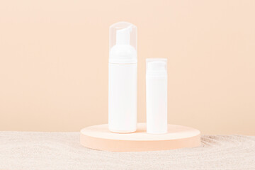 Two white blank plastic packaging cosmetic pump bottles for mousse foam cream and lotion stand on...