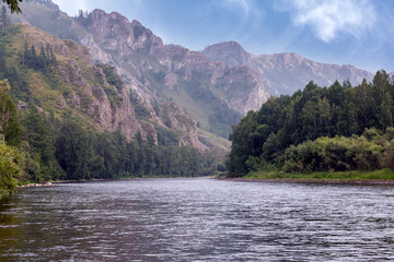 A river and forested mountains along its banks. Summer landscape, beauty of nature.