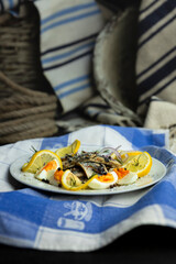 Herring fish fillets with eggs, herbs, onion and lemon on a white plate