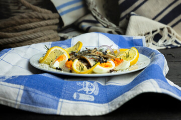 Herring fish fillets with eggs, herbs, onion and lemon on a white plate
