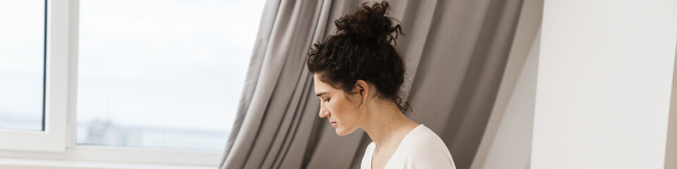 Fototapeta premium The woman looking at the phone while sitting on the bed in a room