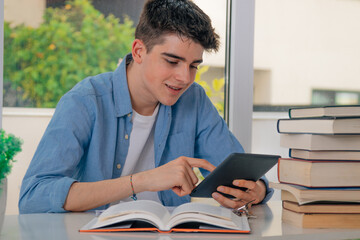 student with computer or tablet at desk with books