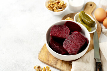 Ingredients for a salad on a light gray culinary background. Beets, walnuts, pickled cucumbers, eggs and mayonnaise on the kitchen table closeup