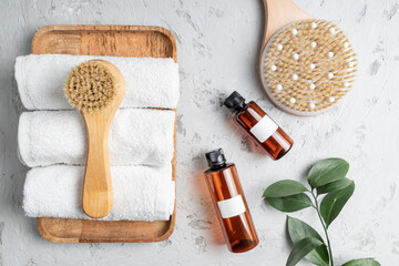 Fototapeta na wymiar Spa body care concept. Anti cellulite cosmetics, Wooden brush for dry massaging and white cotton towel on a bathroom table. Skin care concept