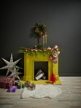 Christmas concept in the grey room with yellow fireplace, wood and Noel objects.