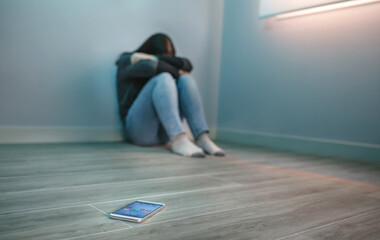 Unrecognizable woman covering her face desperate for cyberbullying with mobile on the floor