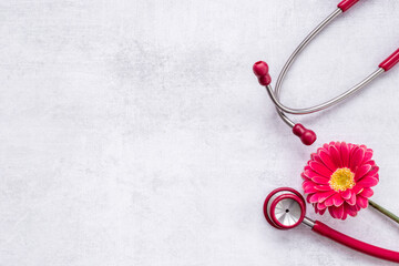 Fototapeta na wymiar Breast cancer awareness concept with red flower and stethoscope