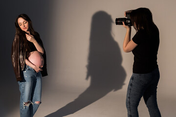 pregnant woman at a photo shoot in the studio, process of photoshooting. Photographer with model