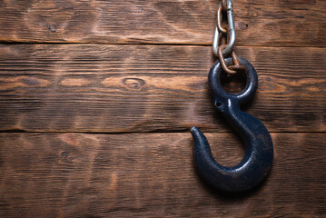 Construction hook on the chain on the wooden flat lay background with copy space.