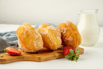Hawaiian malasada donuts on a white table on a wooden board.